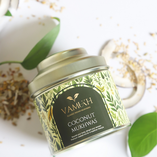 VAMUKH Coconut Mukhwas in a premium tin with pink and white flakes, styled alongside dried rose petals and a brass spoon on a pastel Indian backdrop.