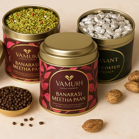 Premium VAMUKH gifting tins – Banarasi Meetha Paan, Chocolate Saunf, and Silver-Coated Mukhwas arranged elegantly on beige stone with brass accents.